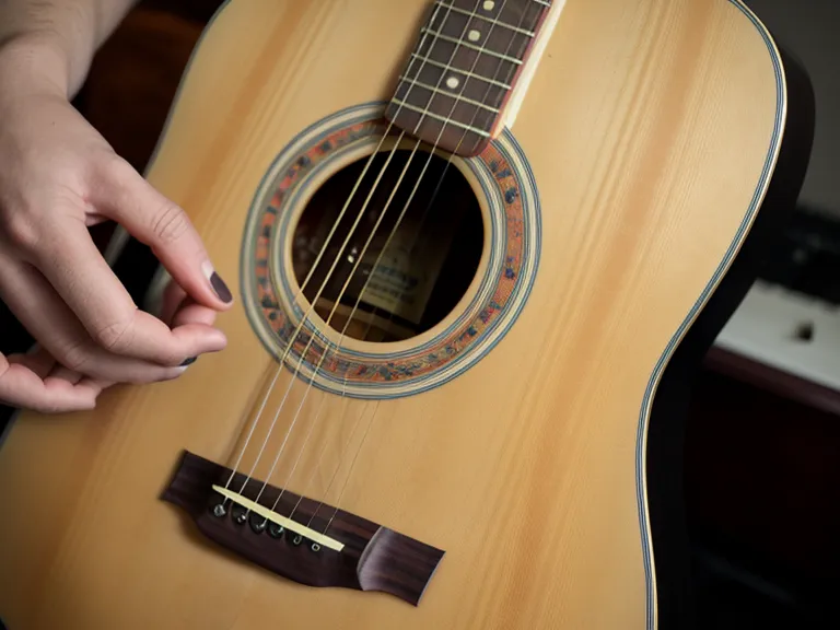 Manos de trabajador descansando junto a una guitarra acústica en una mesa de madera.